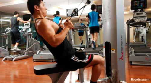 a man sitting on a treadmill in a gym at Weihai Haiyue Jianguo Hotel in Weihai