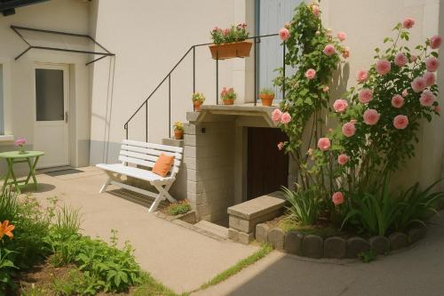 a patio with a bench and flowers in a yard at Petite maison étape Loire à vélo ou Compostelle in Mosnes