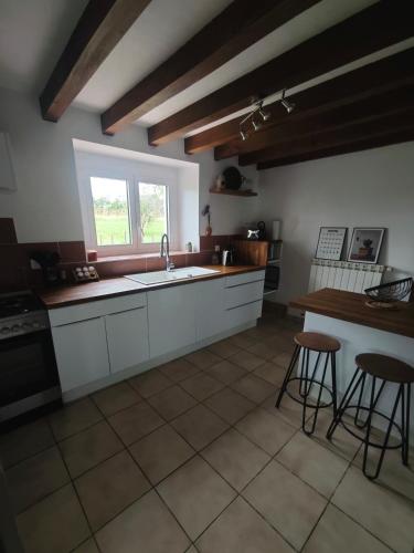 une cuisine avec des armoires blanches, un évier et une fenêtre dans l'établissement Authentic farm stay, à Pouillon