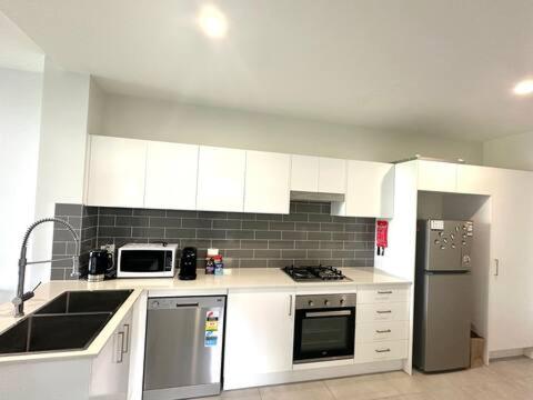 a small kitchen with white cabinets and appliances at 2bedroom 2bath in Garden city in Brisbane