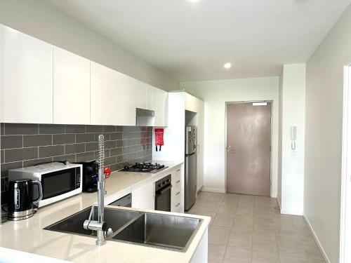 a kitchen with a sink and a microwave at 2bedroom 2bath in Garden city in Brisbane