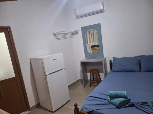 a bedroom with a bed and a refrigerator and a table at KAFUL APARTMENTS in Qeparo