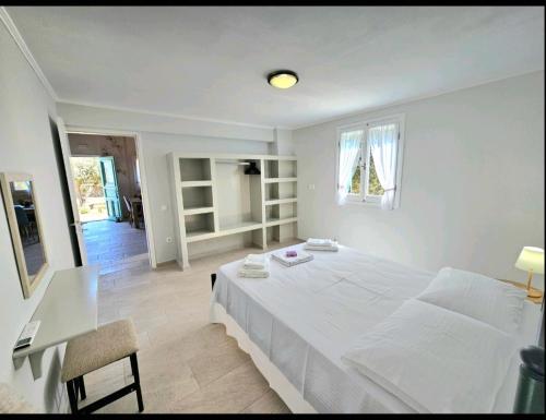 a white bedroom with a large bed and a desk at OLiVE HOUSE in Vathi, Ithaka