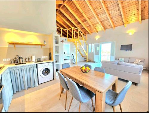 a kitchen and living room with a wooden table and chairs at OLiVE HOUSE in Vathi, Ithaka