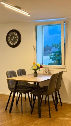 a dining room table with chairs and a clock on the wall at Oldtown central - amazing views in Unterseen