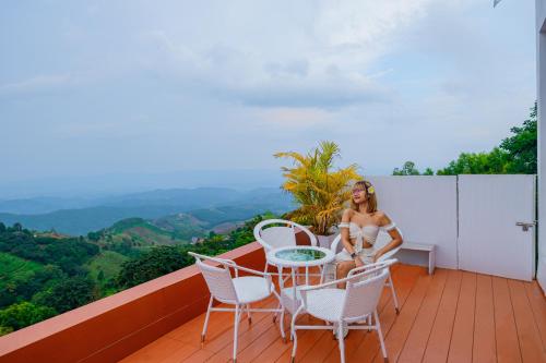 a woman sitting on a balcony with a table and chairs at Maemon villa แม่มอญ วิลล่า in Ban Ri So