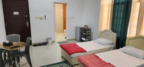 a small room with two beds and a table at Muscat Airport Guesthouse All Private Ensuite Rooms in Muscat