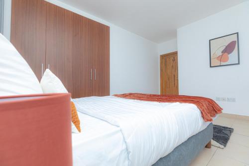 a bedroom with a large bed with white sheets at POLO HEIGHTS-Sky Suites in Accra
