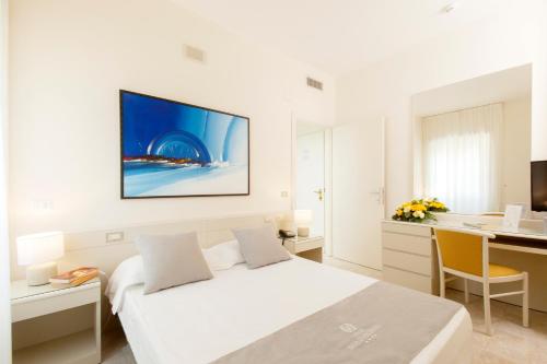 a white bedroom with a bed and a desk with a computer at Baia D'Argento in Porto Santo Stefano