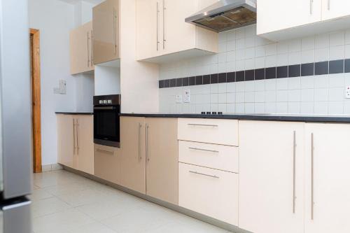 a kitchen with white cabinets and black appliances at POLO HEIGHTS-Sky Suites in Accra