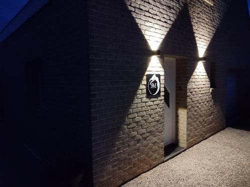 a brick wall with a door with lights on it at Le repaire de Mélusine - Gîte de charme et love room in Sainte-Marie-Cappel
