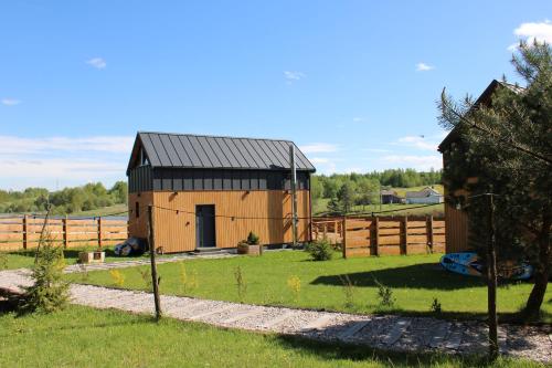 a brown barn with a black roof in a yard at Domki Fajnie.Tu in Łączna