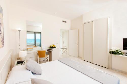 a white bedroom with a bed and a desk at Baia D'Argento in Porto Santo Stefano