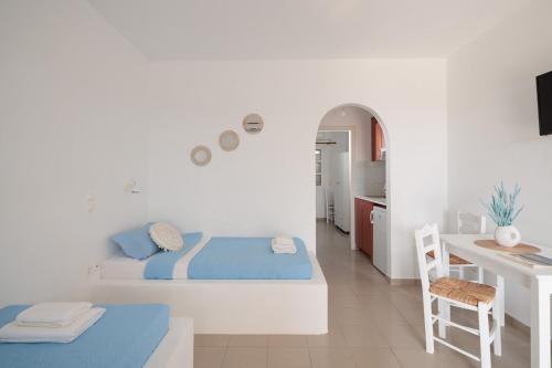 Cette chambre blanche comprend un lit et un bureau. dans l'établissement Aurea Blu Studio 01, sun, beach and dreamlike, à Plage d'Aliko