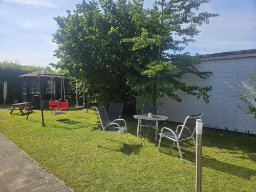 a yard with chairs and a table and a tree at Villa Viktoria Whg 16 - "Auskuck" in Kölpinsee