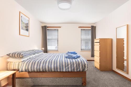 a bedroom with a bed and a dresser and windows at Starfish Accommodation in Whitby