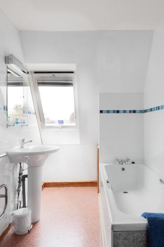 a white bathroom with a tub and a sink at Starfish Accommodation in Whitby