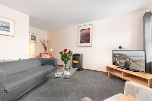 a living room with a gray couch and a tv at Starfish Accommodation in Whitby