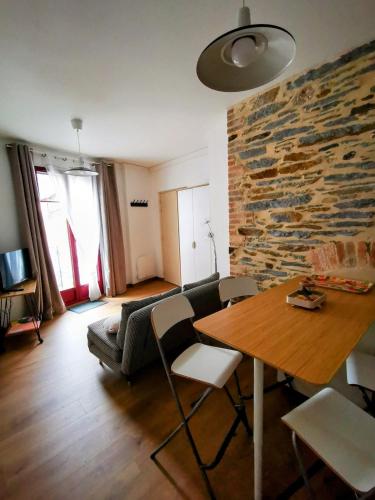 un salon avec une table et un mur en pierre dans l'établissement La Basque - un balcon au coeur de La Gacilly, à La Gacilly