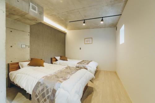 two beds in a room with white walls at 熱海デサイナーズヴィラitsumo in Atami