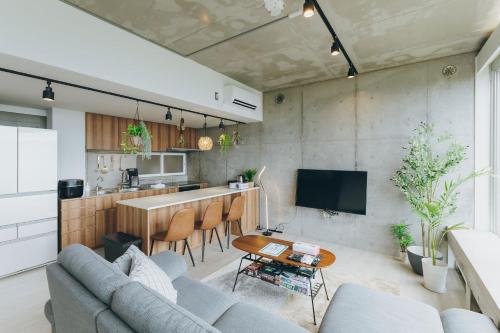 a living room with a couch and a kitchen at 熱海デサイナーズヴィラitsumo in Atami