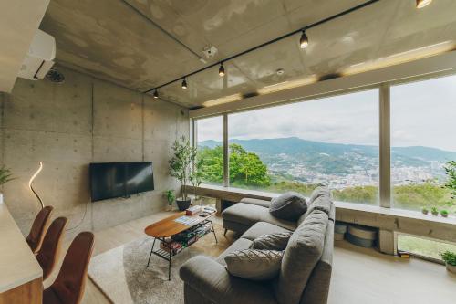 a living room with a couch and a large window at 熱海デサイナーズヴィラitsumo in Atami