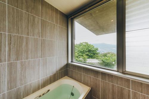 a bathroom with a bath tub and a window at 熱海デサイナーズヴィラitsumo in Atami
