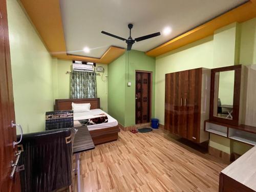 a bedroom with green walls and a bed and a mirror at Maa Sumthira Lodge in Majuli