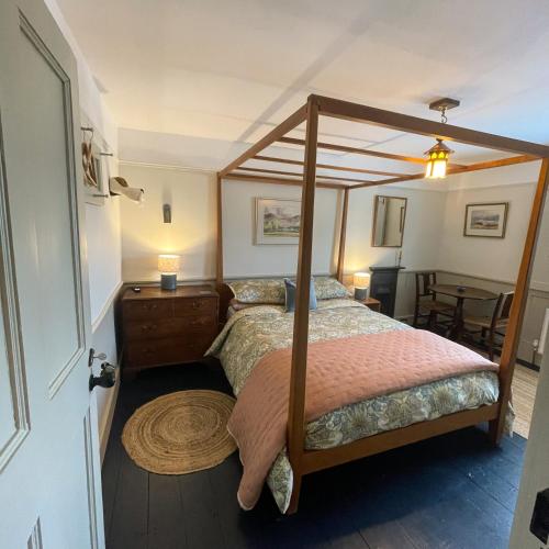 a bedroom with a canopy bed and a table at Helvellyn Cottage in Penrith