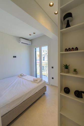 a white bedroom with a bed and shelves at Anna's Corfu Cozy Apartment in Corfu
