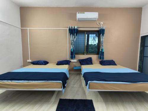 two beds in a room with blue and white at Krishna Garden and Resort in Betgaon