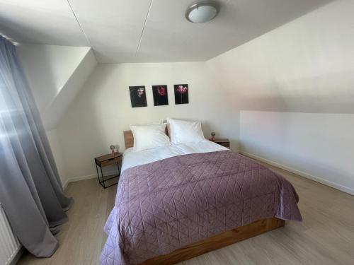 a bedroom with a bed and two pictures on the wall at Wendy's Tiny Beachhouse in Noordwijk