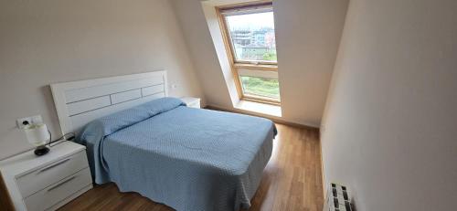a small bedroom with a bed and a window at Ático Paraíso in San Ciprián