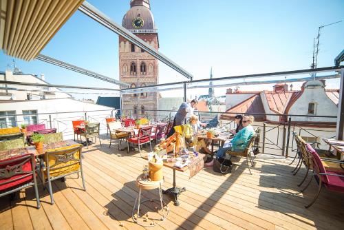 a balcony with people sitting at tables and a clock tower at Hotel Gutenbergs in Riga