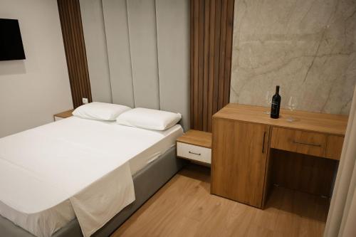 a small bedroom with a bed and a bottle of wine at Vila Venezia in Shëngjin