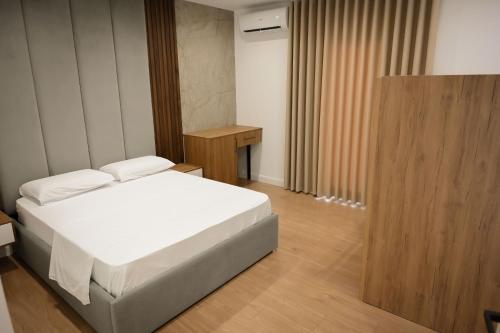 a bedroom with a white bed and a wooden floor at Vila Venezia in Shëngjin