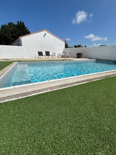 - une grande piscine avec 2 chaises dans la cour dans l'établissement Longère pornicaise avec piscine chauffée, à Pornic