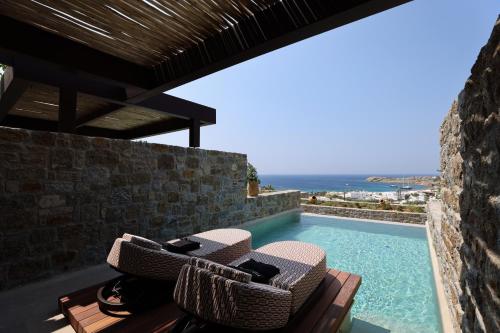 a villa with a swimming pool and two chairs at Tropicana Hotel , Suites & Villas Mykonos in Paradise Beach