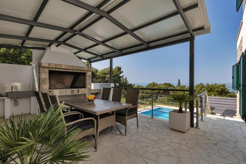 an outdoor patio with a wooden table and a fireplace at Villa la Perla in Baška Voda