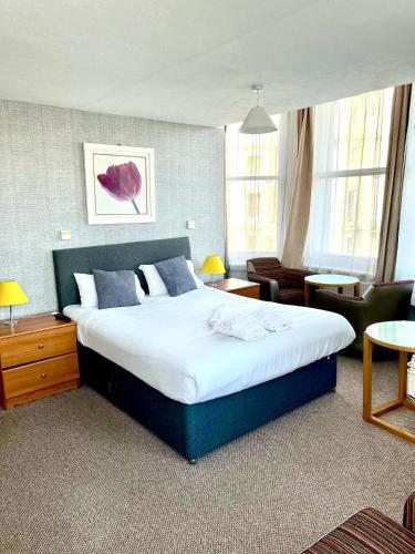 a bedroom with a large bed and a living room at Carlton Court Hotel Eastbourne in Eastbourne