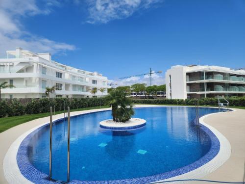 a large swimming pool with a palm tree in the middle at ELEVENLIGHTS-COSTABALLENA Garden View in Costa Ballena