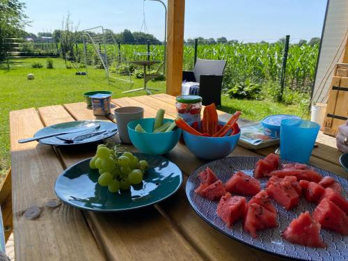 a wooden table topped with plates of fruit and vegetables at Ferienwohnung Lampe in Altenberge