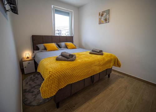 a bedroom with a bed with yellow sheets and a window at Apartman Lakers in Ostrovo