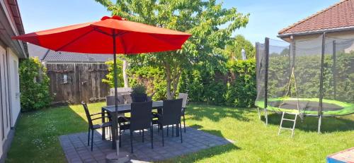 a table and chairs with an umbrella in a yard at Theunis Ferienwohnung in Ostseebad Karlshagen