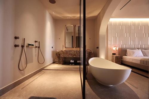 a bathroom with a bath tub and a bedroom at Tropicana Hotel , Suites & Villas Mykonos in Paradise Beach