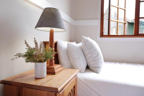 a table with a lamp on a bed with pillows at Highlands Lodge Mountain Retreat in George