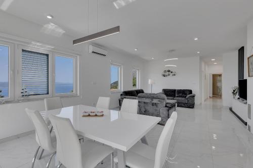a white dining room with a white table and chairs at Villa la Perla in Baška Voda