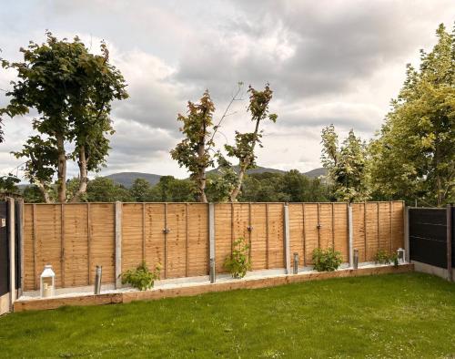 a wooden privacy fence with plants in a yard at Spacious two bedroom home. Easy stroll from Kenmare town in Kenmare