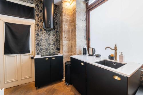 d'une cuisine avec des placards noirs, un évier et une fenêtre. dans l'établissement Studio proche tour Eiffel - paris 15 -2P, à Paris