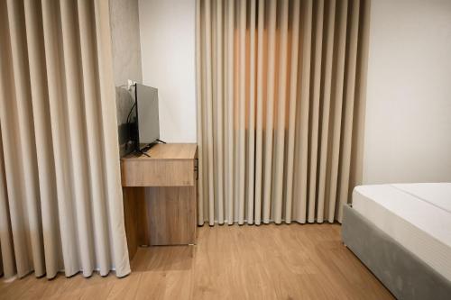 a bedroom with a bed and a tv and curtains at Vila Venezia in Shëngjin